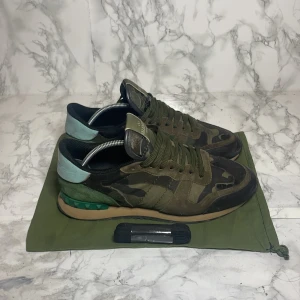 Valentino Rockrunner - Snygga Valentino Rockrunner i storlek 40.5 passar 41 och 40 sneakers med ett coolt camouflagemönster. Skorna är i bra skick har en unik kombination av gröna och blå nyanser med en stilren snörning. De är tillverkade i en mix av mocka och syntetmaterial, vilket ger en lyxig känsla.