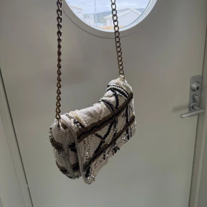 Väska med detaljer  - En jättefinväska som använts men i bra skick!! Tyvärr kommer den inte längre till användning🤍den är rymlig med guldkedja