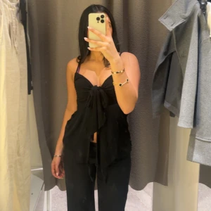 Svart knytblus - Snygg svart blus med knytning framtill och smala axelband. Perfekt för en stilren look. Köpt från GinaTricot för 200kr använt ett par gånger. 