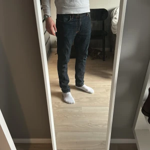 Mörkblå jeans med kontrastsömmar - Snygga mörkblå nudie jeans med kontrastsömmar och klassisk femficksdesign. Perfekta för en avslappnad stil. Tillverkade i slitstarkt denim.