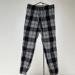 Svartvita rutiga pyjamasbyxor. - Säljer ett para snygga svartvit-rutiga pyjamasbyxor med elastisk och snörad midja. Passar utmärkt för en bekväm och stilren look. Passar bra till både vardag och avslappnade tillfällen. Aldrig använda pga för liten storlek och har bara legat i garderoben sedan dess.