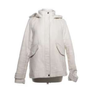 Vit parkajacka med huva - Snygg vit parkajacka med huva och praktiska fickor framtill. Jackan har långa ärmar och stängs med dragkedja och knappar. Perfekt för kyligare dagar.