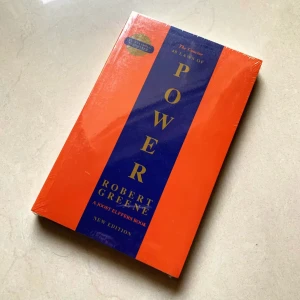 The Concise 48 Laws of Power - Säljer 'The Concise 48 Laws of Power' av Robert Greene. Denna nya utgåva är fortfarande inplastad och har en iögonfallande design med en orange och blå omslag. Perfekt för den som är intresserad av maktstrategier och personlig utveckling.