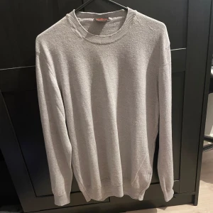 Grå merinoullströja från Oscar Jacobson - Säljer en stilren grå tröja från Oscar Jacobson i storlek M. Tröjan har en klassisk design med rund hals och långa ärmar. Perfekt för en avslappnad men ändå elegant look.