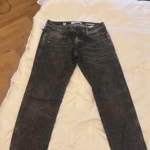 Svarta jeans från Replay - Snygga svarta Replay Anbass jeans med en cool tvättad look. De har en klassisk femficksdesign och knappar i midjan. Perfekta för en stilren vardagslook.