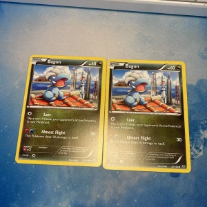 Bagon Pokémonkort - Två Bagon Pokémonkort med 60 HP. Kortet har attackerna Leer och Almost Flight. Perfekt för samlare eller Pokémon-entusiaster!