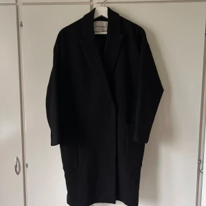 Kappa Carin Wester - Svart oversized kappa från Carin Wester. Superskön och håller värmen (50% ull)   Bra skick men använd, har lite noppror men annars inga anmärkningar.  Strl. 36/S.
