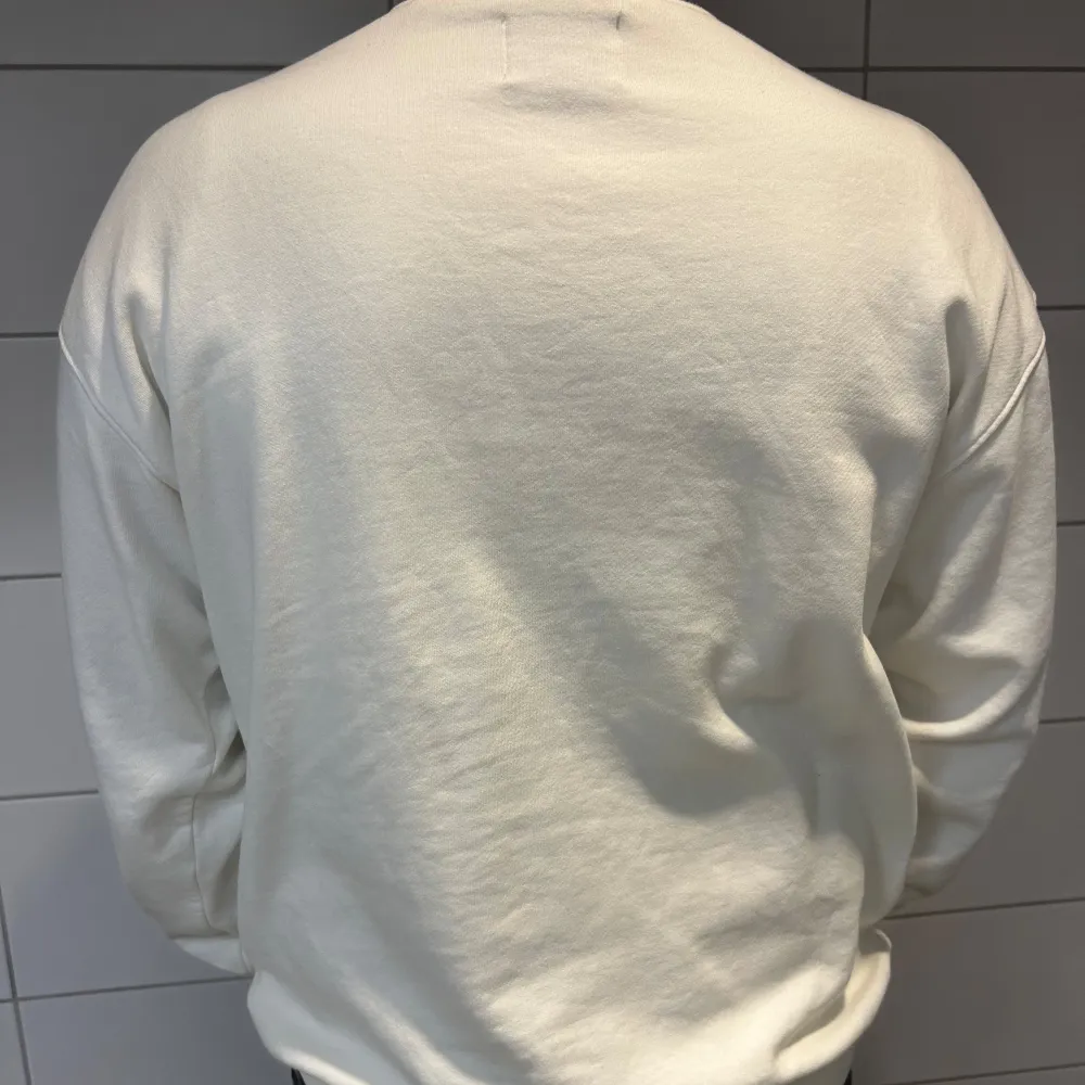 Säljer en snygg vit sweatshirt med grön text 'PARADISE' på framsidan. Tröjan är långärmad och har en normal passform. Perfekt för en avslappnad stil och passar till alla tillfällen. Superbekväm och stilren!. Tröjor & Koftor.