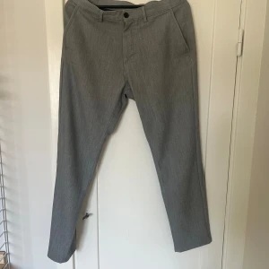 Grå kostymbyxor från Zara - Säljer ett par stilrena grå kostymbyxor från Zara. De är i storlek EUR 42 och har en klassisk passform med raka ben. Byxorna har två sidofickor fram och två bakfickor med knappar. Perfekta för både kontoret och festligare tillfällen!