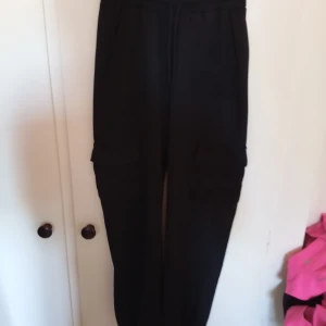 Svarta mjukisbyxor från Gina Tricot - Säljer ett par svarta mjukisbyxor från Gina Tricot i storlek XS. De är superbekväma och perfekta för en avslappnad dag hemma eller en snabb tur till affären. Byxorna har en elastisk midja för extra komfort.