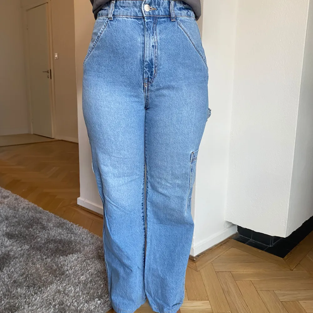 Säljer ett par snygga blå jeans från H&M. De har en hög midja och en straight passform som ger en klassisk look. Jeansen har praktiska fickor både fram och bak, och är perfekta för vardagsbruk. Storleken är EUR 36, vilket motsvarar dam S. de är även stretchiga och supersköna.. Jeans & Byxor.