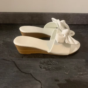 Klackskor med vit rosett  - Storlek 36 men passar mig som har 37. Använda en dag.  