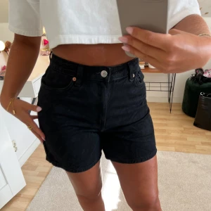 Svarta jeansshorts - Snygga svarta jeansshorts med mellanhög midja. Sitter snyggt i rumpan. Storlek 26. Är 167 cm lång.
