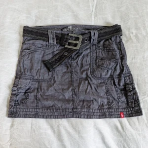 Grå kjol från Esprit - Säljer en supercool grå cargokjol från EDC by Esprit. Storlek 40. Kjolen har en avslappnad stil med flera fickor både fram pch baktill och ett snyggt bälte med ett chunky metallspänne. Perfekt för en casual vintage look! 🖤