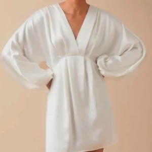 Vit klänning från Gina Tricot - Säljer en vit satin klänning från Gina Tricot i storlek 36. Klänningen har en v-ringad design och långa ärmar med rynkade detaljer. På ena baksidan av armen finns en liten fläck. Den finns inte längre på Gina tricos sidor. Fråga om mer bilder💗