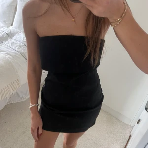 Svart axelbandslös klänning  - En super snygg och stilren svart tub-klänning. Det finns genomskinliga band om man vill vara säker på att klänningen sitter på plats. Aldrig använd. Passar till finare tillställningar🩷