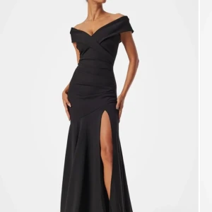 Balklänning  - Hade den själv på min bal och tänker sälja den nu eftersom den ej kommer till användning. Elegant svart långklänning med en djärv slits framtill. Klänningen har en offshoulder-design som ger en sofistikerad look. Perfekt för speciella tillfällen där du vill sticka ut. Perfekt för mig som är 163 cm då jag kortade ner den några cm men inte mycket skillnad alls