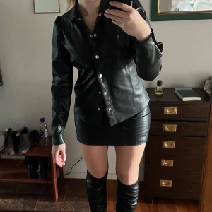 Set Svart skinnblus och minikjol - Snygg svart skinnjacka / blus och kort kjol🖤 Jackan har en stilren design med långa ärmar och en klassisk krage. Perfekt för fest. Kjolen är från Gina Tricot och blusen från Kappahl. Kan säljas separat också