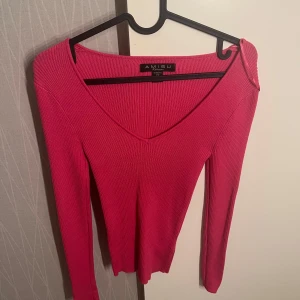 Rosa ribbad tröja från Amisu - Säljer en snygg rosa ribbad tröja från Amisu. Tröjan har en v-ringad design och långa ärmar, perfekt för både höst och vår. Den är gjord i ett stretchigt material som ger en bekväm passform. Oanvänd 