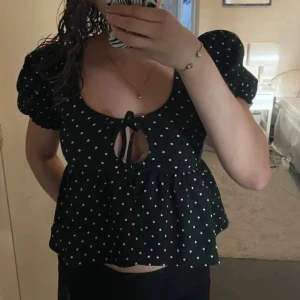 Svart prickig topp med knyt - Säljer en söt svart topp från Gina med vita prickar och knyt framtill‼️lånad bild!!‼️