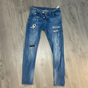 Blå jeans från Dsquared2 - Snygga blå jeans från Dsquared2 med slitna detaljer och en cool, distressed look. De har en knappgylf och klassisk femficksdesign. Perfekta för en avslappnad stil med en touch av edge.