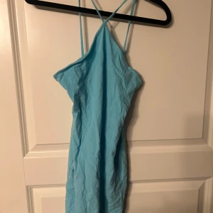 Ljusblå klänning med smala axelband - Säljer en söt ljusblå klänning med smala axelband och korsad rygg. Perfekt för varma sommardagar eller en dag på stranden. 