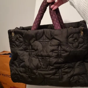 Svart Pillow monogram bag väska - Säljer en elegant svart quiltad pillow monogram väska med ikoniskt Louis Vuitton mönster. Väskan har vadderade handtag i brunt med monogram och en praktisk dragkedja. Perfekt för dig som vill ha stil och funktion i ett. Har fått den i present men aldrig använt den. Kommer utan äkthetsintyg, därav det låga priset