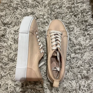 Beige sneakers från H&M - Snygga beige/ rosa sneakers från H&M med vit platåsula och klassisk snörning. De är i bra skick men som ni ser på sista bilden så har de en knut på snöret, hör av er för frågor eller annat💞💞