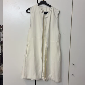 Vit väst med knäppning - Elegant vit väst med stilren design och knäppning framtill. Västen har en rak passform och är perfekt för att lägga till en touch av elegans till din outfit.