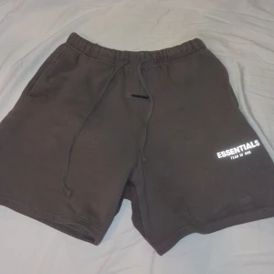 Shorts från Essentials - Snygga bruna shorts från Essentials med elastisk midja och dragsko. Perfekta för en avslappnad stil. Essentials-logga tryckt på benet ger en trendig touch.