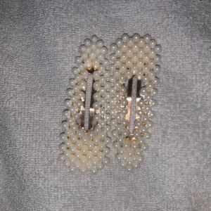 Hårspännen med pärlor. Aldrig använt - Säljer ett par eleganta hårspännen dekorerade med vita pärlor. Perfekta för att ge en stilfull touch till din frisyr. De har en stabil metallklämma som håller håret på plats.