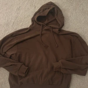 Brun hoodie från 157 - Säljer en brun hoodie från märket 157. Den har en klassisk design med huva och dragsko, samt långa ärmar. Perfekt för en avslappnad stil.