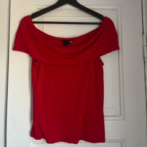 Röd offshoulder topp från H&M - Snygg röd offshoulder topp från H&M. Perfekt för en trendig look med sin axelbandslösa design. Tillverkad i ett mjukt och bekvämt material som ger en skön passform.