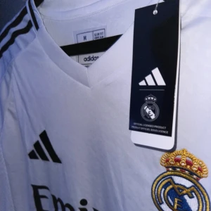 Real madrid första kit/ställ säsongen 24/25 - Säljer en vit Real Madrid fotbollströja från Adidas. Har allt org kvar och har bara testat på en gång men den var för liten för mig. Annars passar den true to size. Skriv om du har några funderingar.