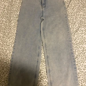 Ljusblå jeansbyxor - Snygga ljusblå jeansbyxor med hög midja och rak passform. Perfekta för en avslappnad stil. De har klassiska femficksdetaljer och en dragkedja framtill.