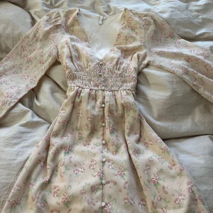 Blommig klänning  - Blommig rosa-beige klänning från Nelly. Jättesöt och bra skicka överlag förutom en sminkfläck som går att se på sista bilden. 