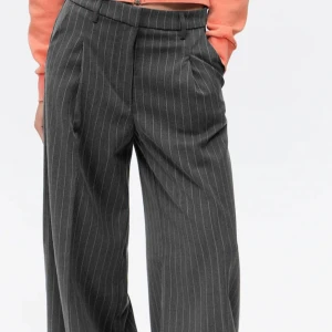 Grå randiga kostymbyxor - Snygga grå kostymbyxor med diskreta ränder. Byxorna har en hög midja och en vid passform som ger en elegant look. Perfekta för en stilren outfit. Stl 158 men passar mig som vanligtvis har s/m