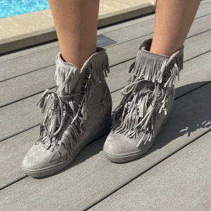 Grå boots med fransar - Snygga grå boots med fransar och snörning. De har en kilklack och är fodrade med mjukt material för extra komfort. Perfekta för en trendig look.