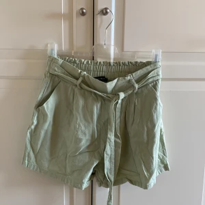 Ljusgröna shorts från Amisu - Snygga ljusgröna shorts från Amisu med elastisk midja och knytband. Perfekta för varma dagar med en avslappnad passform. Shortsen har praktiska fickor på sidorna och är tillverkade i ett lätt och bekvämt material. Från New Yorker. Storlek 40. Helt okej i skicket.