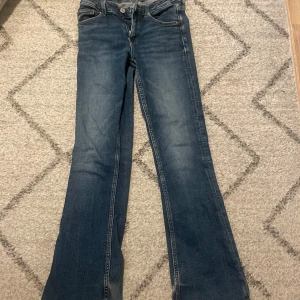 Blå bootcut jeans från Gina Tricot - Snygga blå bootcut jeans från Gina Tricot. De har en klassisk femficksdesign och en bekväm passform. Perfekta för en avslappnad stil med en touch av retro.