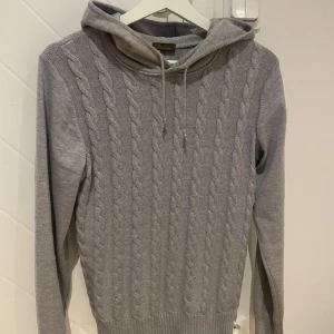 Grå stickad hoodie från Stenströms - Säljer en stilren grå stickad hoodie från Stenströms med kabelstickat mönster. kontakta för fler bilder eller vid intresse.