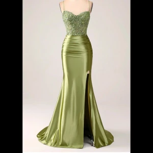 Grön balklänning med slits💚 - Jag säljer nu min vackra balklänning. Elegant grön bal klänning i satin med en vacker slits framtill och snörning i ryggen. Överdelen är dekorerad med paljetter som ger en glittrig effekt. Perfekt för bal💚.        Pris kan diskuteras!