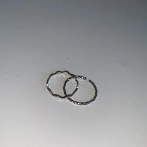 Silvriga ringar med vågig design - Två stilrena silvriga ringar med en unik vågig design. Perfekta för att ge en subtil men elegant touch till din stil. Passar bra att bära tillsammans eller var för sig.