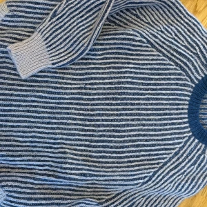 Blå och vit randig tröja från Baum und Pferdgarten - Säljer en snygg blå och vit randig tröja från Baum und Pferdgarten. Tröjan är stickad med långa ärmar och har en rund halsringning. Perfekt för kyliga dagar!