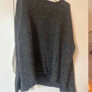 Grå stickad tröja - Mysig grå stickad tröja med lång ärm och en djup v-ringning i ryggen.