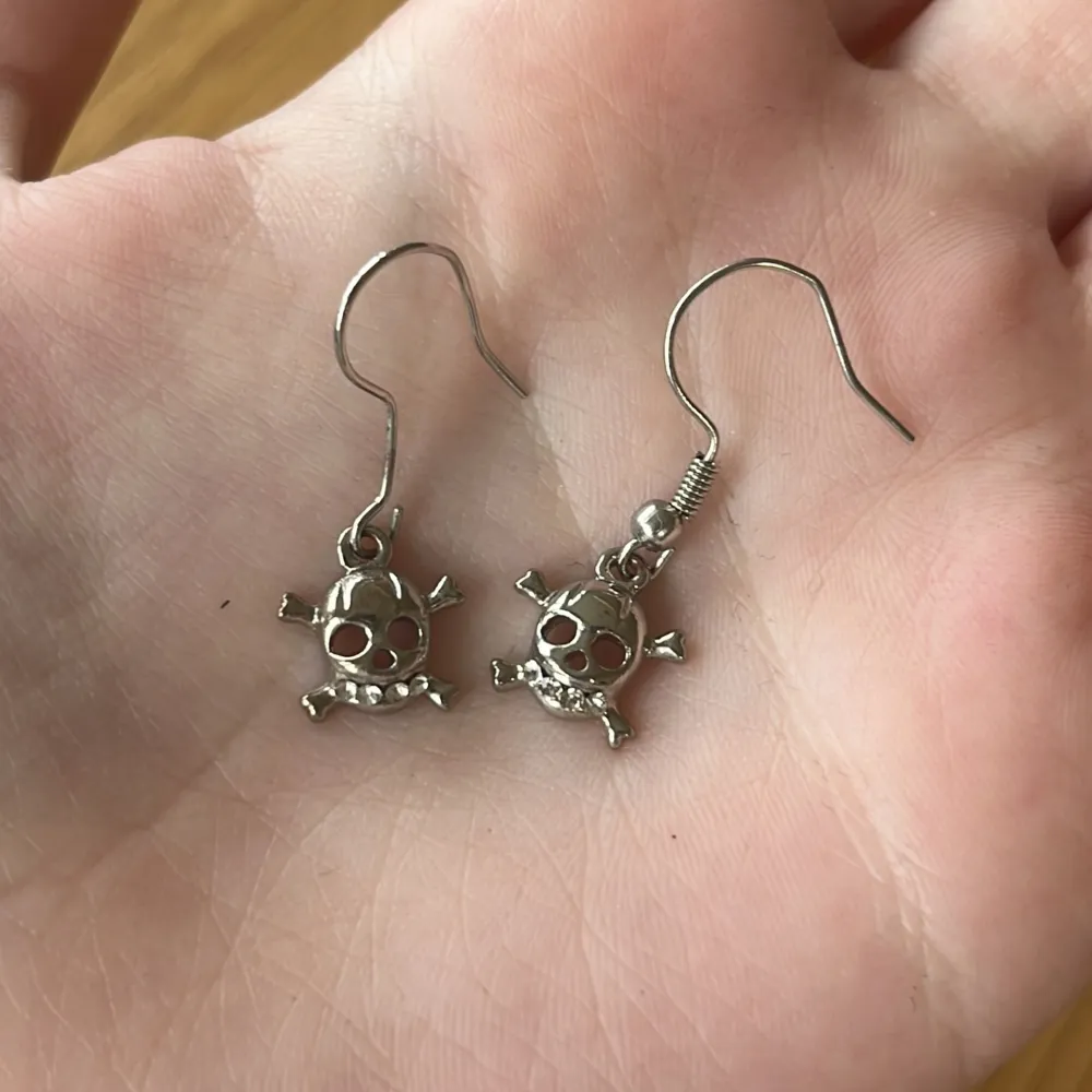 Coola örhängen i form av dödskallar i silverfärg, dekorerade med stenar. Säljer då jag inte använder silver. Kommer tyvärr inte ihåg varför det inte är samma krokar på örhängena, men detta påverkar inte användningen eller kvaliteten. Örhängena är noga tvättade och disinfekterade. Märket är okänt.. Asusteet.