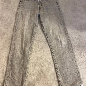 Grå jeans från Jack & Jones - Snygga grå jeans från Jack & Jones i modellen Relaxed/Chris. De har en avslappnad passform med klassisk femficksdesign och knappgylf. Perfekta för en casual look.