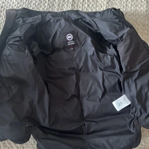 Svart dunjacka från Canada Goose - Säljer en svart dunjacka från Canada Goose, modellen heter Macmillan. Skicket på jackan är 10/10 då jag aj använt den så mycket! Kvitto och äkthets bevis tar vi i DM! NYPRIS 14 000kr
