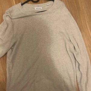 Beige tröja från Jack & Jones - Säljer en stilren oanvänd beige tröja från Jack & Jones. Tröjan har en klassisk rund hals och långa ärmar, perfekt för en avslappnad look. Passar bra till både jeans och chinos.