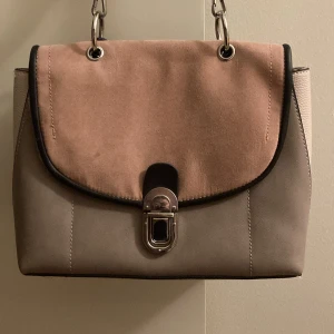 Beige och rosa handVäska/axelväska med silver detaljer - Helt ny snygg rosa och beige väska med silver detaljer, den kan andvändas som handVäska och Axelväska, man kan ta bort Axel repet och sätta tillbaka. Den har aldrig andvänds eftersom att det inte är min stil, inga skador eller repor. PRISET KAN DISKUTERAS OM FÅTAL ÄR INTRESSERADE!💗